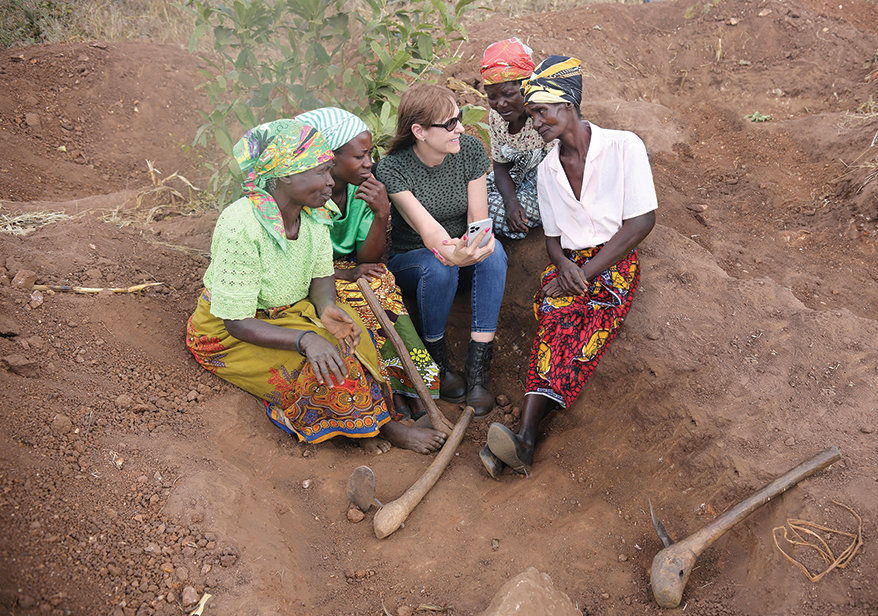 Susan Wheeler (below center) shows one of her Malawi rhodolite necklaces on her phone to rhodolite miners in Malawi.